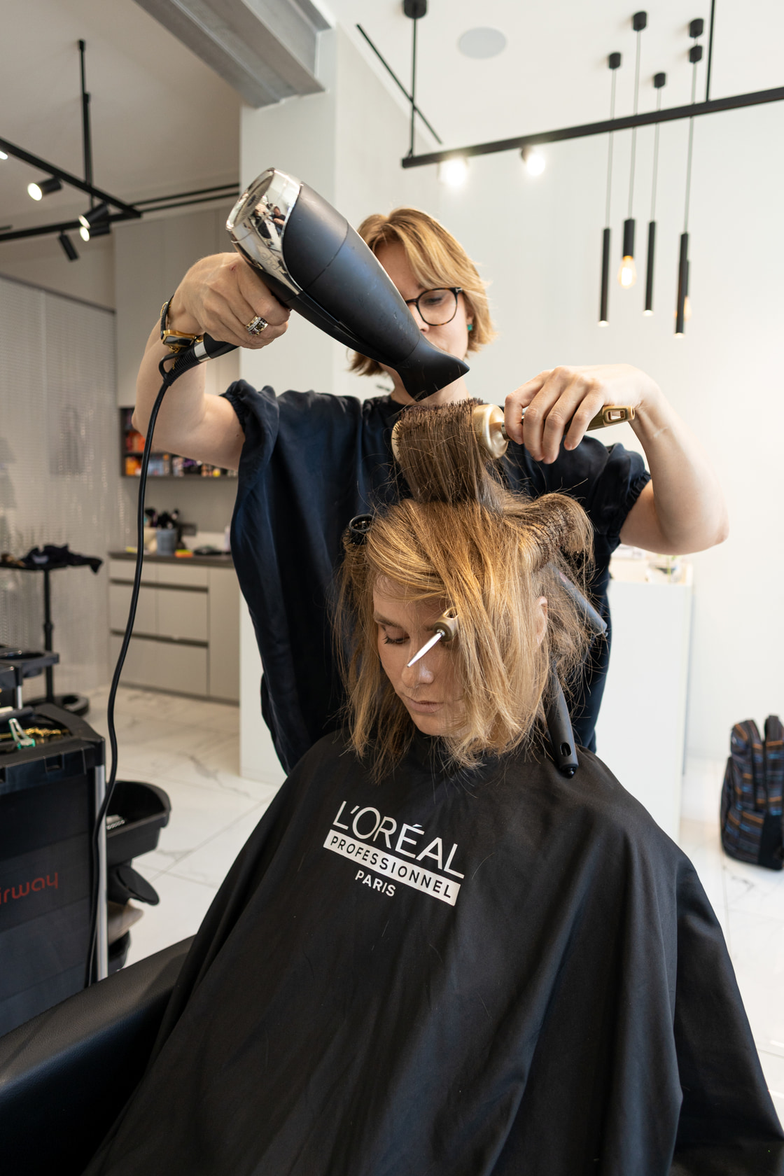 Mise en forme au séchoir et à la brosse ronde sous les lumières du salon